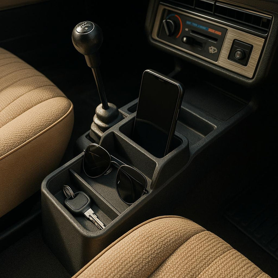 En smartphone, solbriller og bilnøgle i en bils midterkonsol.
