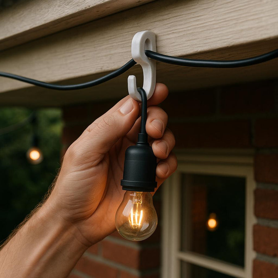 Hånd monterer en lyspære på udendørs ledning.