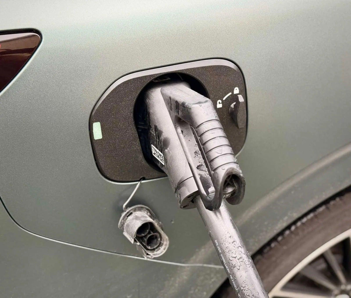 XPENG G9 Ladeport Cover med CCS-stik og hætte hængende i sit kabel